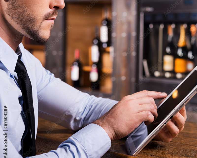 man looking at ipad inside liquor store | ;iquor store POS